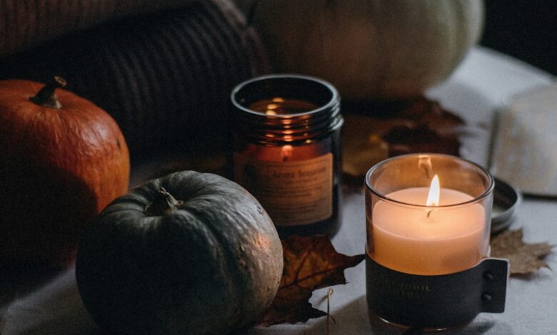 a table topped with a candle next to a pile of pumpkins